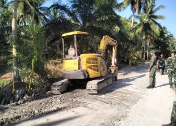 Personel TNI dari Kodim 0419/Tanjab bersama alat berat saat melaksanakan pemadatan jalan dalam program TMMD ke-124 di Desa Kemuning, Kamis (22/5/2025). (Foto: Dok. Nahar - JT)