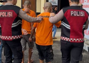 Anggota Polres Merangin menggiring dua tersangka kasus pencurian dengan kekerasan di Desa Sungai Tebal. Sabtu (05/05/2025) (Dok. Humas Polres Merangin)