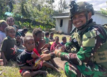 Seorang prajurit Satgas Yonif 700/WYC dari Pos Kout Sinak membagikan makanan ringan kepada anak-anak di Kampung Gigobak, Distrik Sinak, Papua, dalam kegiatan anjangsana sosial. (Dok. Pen Satgas Yonif 700/WYC)