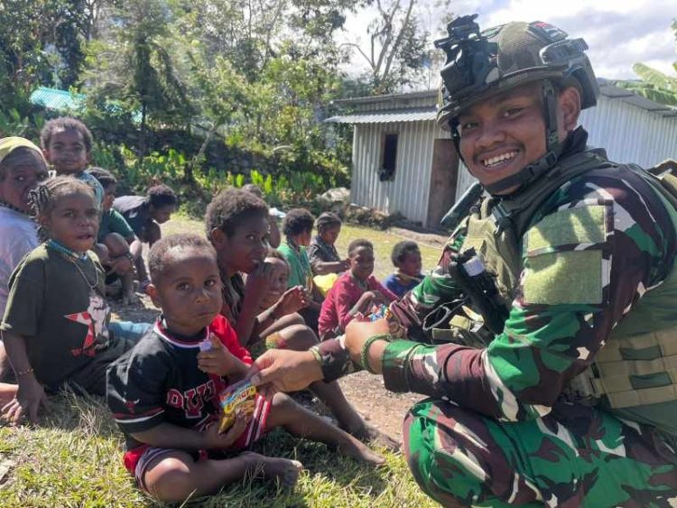 Seorang prajurit Satgas Yonif 700/WYC dari Pos Kout Sinak membagikan makanan ringan kepada anak-anak di Kampung Gigobak, Distrik Sinak, Papua, dalam kegiatan anjangsana sosial. (Dok. Pen Satgas Yonif 700/WYC)
