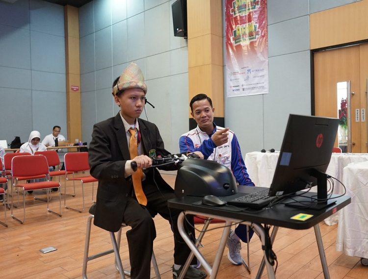 Seorang peserta AHM Best Student tengah mengikuti sesi simulasi presentasi inovasi di hadapan tim pelatih. Didampingi oleh instruktur, peserta mengenakan pakaian adat khas sambil memanfaatkan teknologi digital dalam mendemonstrasikan idenya. Rabu (28/05/2025). (Dok. Sinsnen)