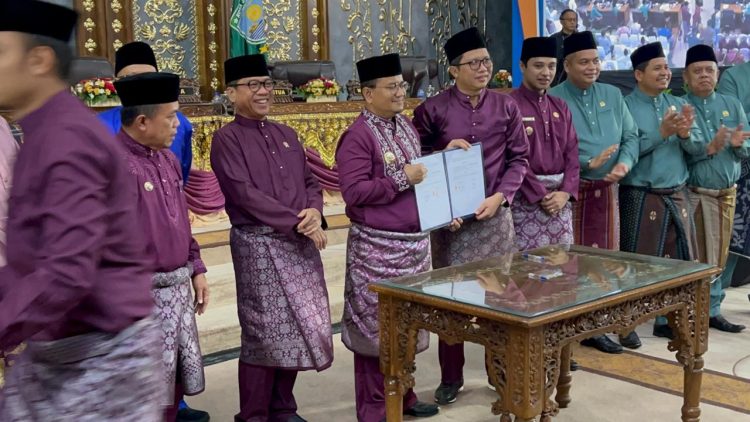 Kepala BPJS Ketenagakerjaan Cabang Jambi, Hendra Elvian (tengah), bersama Wali Kota Jambi, Dr. H. Maulana, MKM, menunjukkan dokumen nota kesepahaman usai penandatanganan MoU perlindungan ketenagakerjaan bagi pekerja non-ASN dan sektor informal di Rapat Paripurna HUT Kota Jambi, Rabu (28/5/2025). (Dok. Yola)