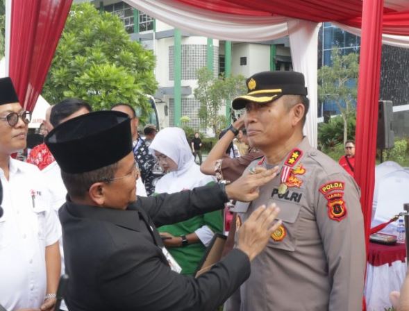 Wali Kota Jambi, Dr. dr. H. Maulana, MKM, menyematkan medali penghargaan PMI kepada AKBP Dr. Dadang Djoko Karyanto dalam peringatan Hari Donor Darah Sedunia di Lapangan Kantor Wali Kota Jambi, Senin (16/6/2025). (Dok. Daus)