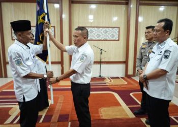 Bupati Muaro Jambi, Bambang Bayu Suseno, menyerahkan bendera pataka kepada Ketua DPC Organda Kabupaten Muaro Jambi yang baru dilantik pada Rabu (7/5/2025) di Aula Rumah Dinas Bupati. (Dok. Kominfo)