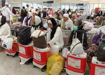 Jamaah haji Indonesia menunggu jadwal keberangkatan di terminal Bandara Arab Saudi dengan koper beridentitas kloter. Mayoritas di antaranya merupakan perempuan dan lansia. (Makkah, 2025). (Dok. mui.or.id)