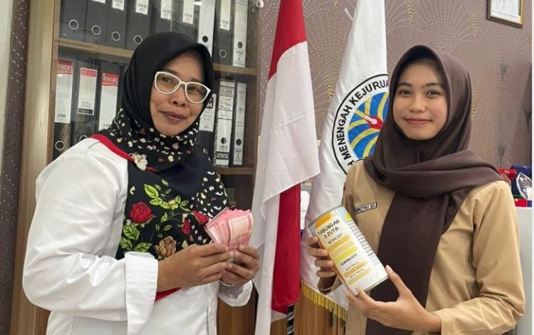 Arumingtyas Khoni Dahlia (kanan), siswi SMAN 3 Kota Jambi yang juga atlet karate, menyerahkan tabungan hasil prestasinya untuk berkurban didampingi gurunya, Kamis (5/6/2025). (Dok. Yola)