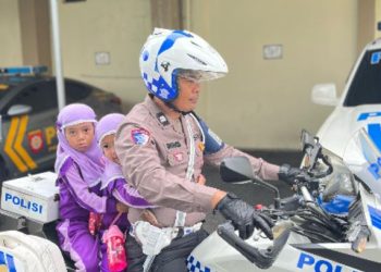Seorang personel Satlantas Polresta Jambi mengajak siswa TK menaiki motor dinas dalam kegiatan Polisi Sahabat Anak di Mapolresta Jambi, Selasa (10/6/2025). (Dok. nahar)