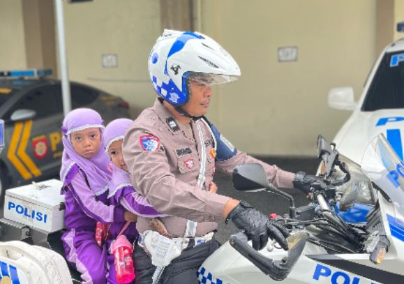 Seorang personel Satlantas Polresta Jambi mengajak siswa TK menaiki motor dinas dalam kegiatan Polisi Sahabat Anak di Mapolresta Jambi, Selasa (10/6/2025). (Dok. nahar)