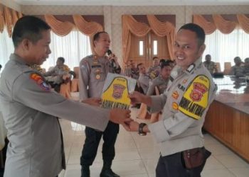 Kasubdit Bhabinkamtibmas Ditbinmas Polda Jambi, AKBP Mustofa Kholil (kiri), menyerahkan Bed Lengan Bhabinkamtibmas kepada personel berprestasi dari Polres Tebo saat kegiatan evaluasi kinerja, di aula Polres Tebo, Kamis (13/6/2025). (Dok. Daus)