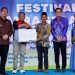 Plt. Manager Pertamina EP Jambi Alfian Mayando menyerahkan dokumen serah terima pengelolaan TK Patra Serandi kepada Kepala Desa Talang Belido, Fadli, disaksikan Bupati Muaro Jambi Bambang Bayu Suseno dalam Festival Patra Serandi, Rabu (12/6/2025). (Dok. Yola)