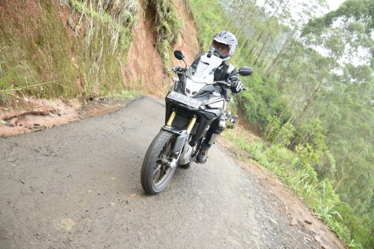 Seorang pengendara motor melintasi jalan sempit dan rusak di kawasan perbukitan. (Foto: Dok. Sinsen)