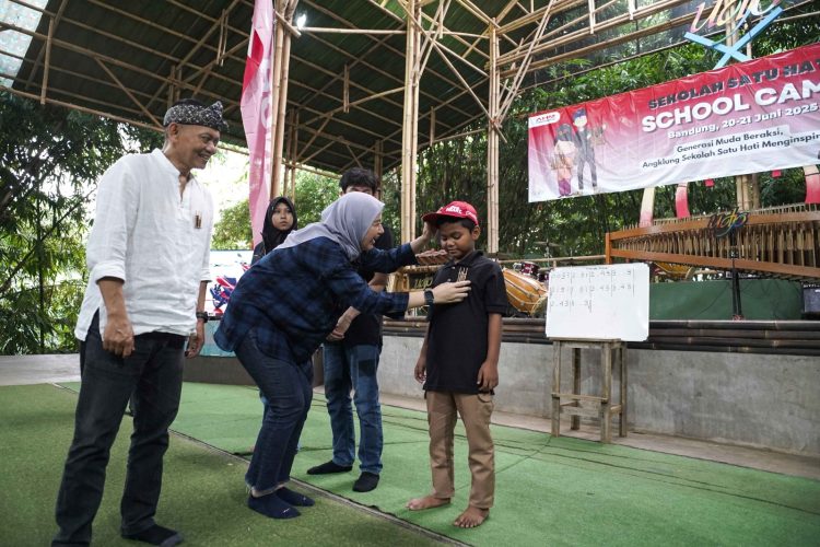 Seorang peserta School Camp 2025 menerima pin duta budaya dari perwakilan AHM dalam rangkaian kegiatan pelestarian angklung di Saung Angklung Udjo, Bandung, Jumat (21/6/2025). (Dok. Sisnen)