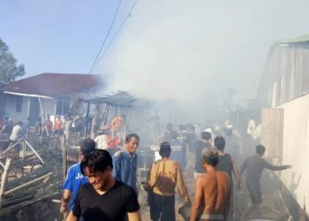 Warga berupaya memadamkan api dan merobohkan bangunan di sekitar lokasi kebakaran di RT 03 Dusun Polewali, Desa Lambur, Kecamatan Muara Sabak Timur, Jambi, Minggu (6/7/2025). (Dok. Nitizen)