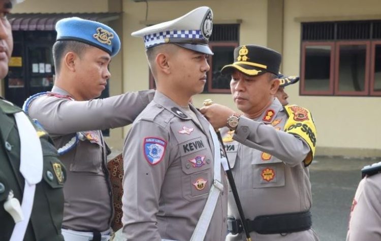 Kapolres Kerinci AKBP Arya Tesa Brahmana, S.I.K., M.H. menyematkan pita tanda dimulainya Operasi Patuh Siginjai 2025 kepada anggota satuan lalu lintas saat Apel Gelar Pasukan di Mapolres Kerinci, Senin (14/7/2025). (Dok. Humas)