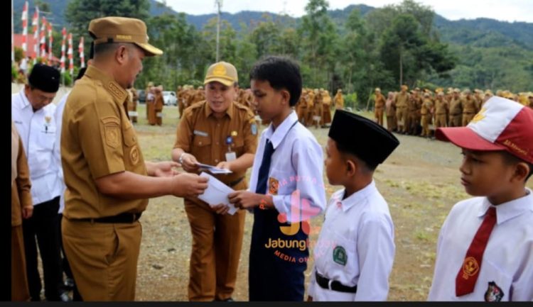 Bupati Kerinci Monadi menyerahkan secara simbolis bantuan pendidikan dari Program Kerinci Cerdas kepada siswa yatim dan terlantar usai apel pagi di halaman Kantor Bupati Kerinci, Senin (7/7/2025). (Dok. Yola)