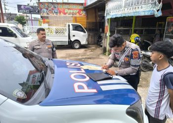 Petugas Satlantas Polresta Jambi menulis surat tilang kepada salah satu pengendara yang melanggar aturan dalam operasi penegakan hukum lalu lintas, Senin (14/7/2025). (Dok. Nahar)