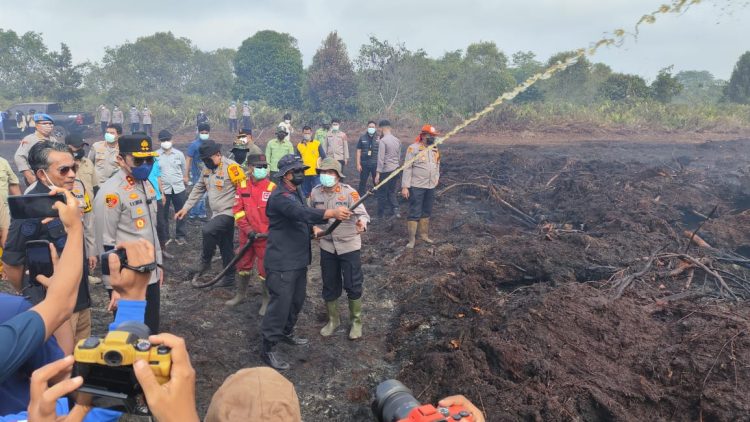 Kapolda Jambi Irjen Pol Krisno H Siregar dan Dansat Brimob Polda Jambi Kombes Pol Muhammad Faishal Aris memantau sekaligus ikut memadamkan kebakaran lahan di Desa Gambut Jaya, Kecamatan Sungai Gelam, Muaro Jambi, Sabtu (26/7/2025). (Dok. Nahar)