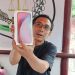 Ketua Umum LPKNI, Kurniadi Hidayat, menunjukkan produk ponsel yang dipesan melalui siaran langsung di TikTok, namun tidak sesuai dengan yang dijanjikan. Barang yang diterima tanpa merek dan tanpa legalitas resmi. (Dok. Stepanus)