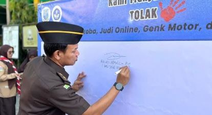 Perwakilan Kejaksaan Negeri Jambi menandatangani dukungan gerakan antinarkoba, antijudi daring, dan geng motor dalam kegiatan "Gerakan Pramuka Goes to School" di SMPN 11 Kota Jambi, Senin (21/7/2025). (Dok, Daus)