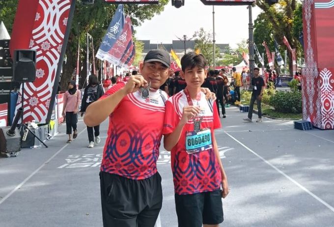 AKBP Dr. Dadang Djoko Karyanto berfoto bersama salah satu pelajar peserta Presisi Merdeka Run 2025 kategori 5K di Lapangan Kantor Gubernur Jambi, Minggu (3/8/2025) (Dok. Nahar)