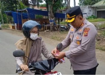 Kapolres Tanjab Timur AKBP Maulia Kuswicaksono membagikan bendera merah putih kepada seorang pengendara di simpang empat Sate, Muara Sabak Barat, Senin (5/8/2025). (Daus)