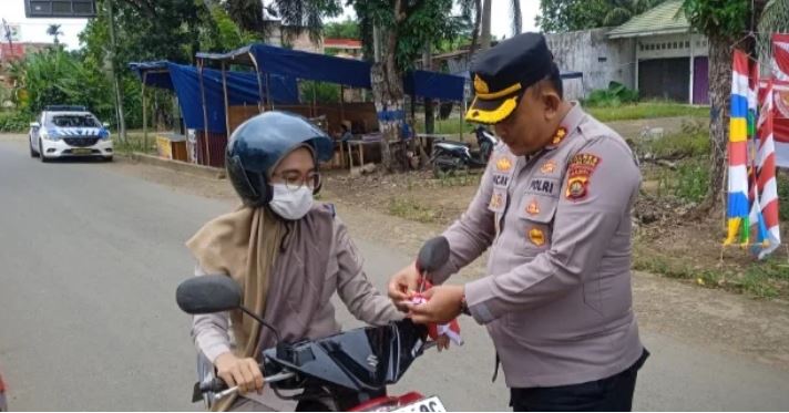 Kapolres Tanjab Timur AKBP Maulia Kuswicaksono membagikan bendera merah putih kepada seorang pengendara di simpang empat Sate, Muara Sabak Barat, Senin (5/8/2025). (Daus)