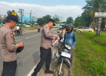 Kapolsek Jaluko, Iptu Yohanes Chandra, S.E., M.H., memasang Bendera Merah Putih di sepeda motor warga yang melintas di depan Mako Polsek Jaluko, Jambi, Rabu (6/8/2025), (Foto: Nahar)