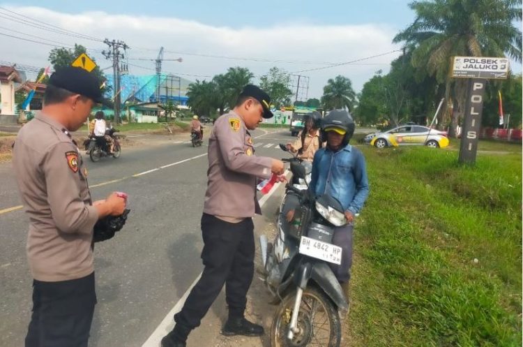 Kapolsek Jaluko, Iptu Yohanes Chandra, S.E., M.H., memasang Bendera Merah Putih di sepeda motor warga yang melintas di depan Mako Polsek Jaluko, Jambi, Rabu (6/8/2025), (Foto: Nahar)