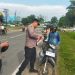 Kapolsek Jaluko, Iptu Yohanes Chandra, S.E., M.H., memasang Bendera Merah Putih di sepeda motor warga yang melintas di depan Mako Polsek Jaluko, Jambi, Rabu (6/8/2025), (Foto: Nahar)