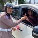 Personel Satlantas Polresta Jambi membagikan bendera Merah Putih kepada pengendara mobil saat kegiatan simpatik menyambut HUT ke-80 RI di Simpang Empat Museum, Kota Jambi, Selasa (12/8/2025). (Dok. Nahar)