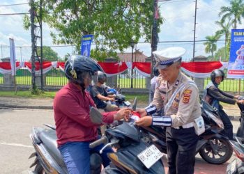 Personel Satlantas Polresta Jambi membagikan bendera Merah Putih kepada pengendara sepeda motor di kawasan simpang empat Museum, Jalan Slamet Riyadi, Kota Jambi, Kamis (14/8/2025) (Dok. Daus)