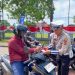 Personel Satlantas Polresta Jambi membagikan bendera Merah Putih kepada pengendara sepeda motor di kawasan simpang empat Museum, Jalan Slamet Riyadi, Kota Jambi, Kamis (14/8/2025) (Dok. Daus)