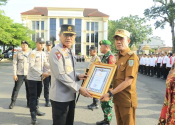 Kapolda Jambi Irjen Pol Krisno H. Siregar menyerahkan piagam penghargaan pada Rapulis, S.E., selaku Lurah Rawasari usai apel pagi di Lapangan Hitam Mapolda Jambi pada Senin (4/8/2025). (Nahar)
