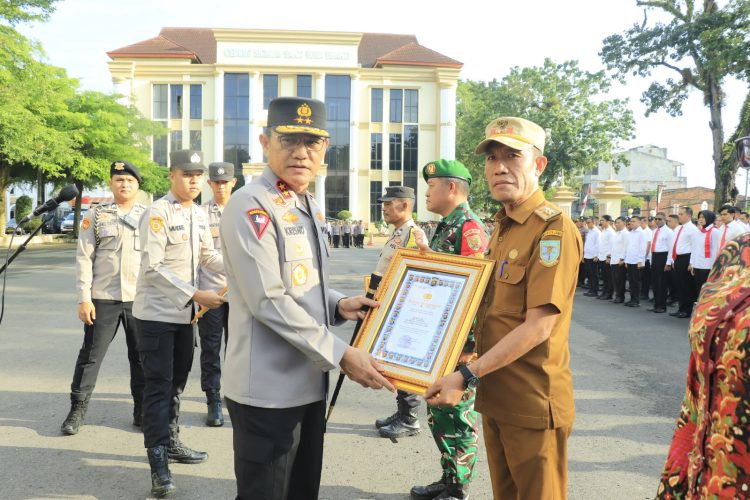 Kapolda Jambi Irjen Pol Krisno H. Siregar menyerahkan piagam penghargaan pada Rapulis, S.E., selaku Lurah Rawasari usai apel pagi di Lapangan Hitam Mapolda Jambi pada Senin (4/8/2025). (Nahar)