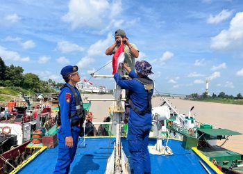 Personel Ditpolairud Polda Jambi membantu memasang bendera merah putih di salah satu kapal warga di Sungai Batanghari, Rabu (6/8/2025), (dok.humas)