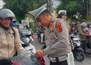 Kasat Lantas Polresta Jambi AKP Hadi Siswanto memasang bendera merah putih di kendaraan salah satu pengendara di Simpang Jelutung, Jambi, Rabu (6/8/2025).(Dok.Stepanus)