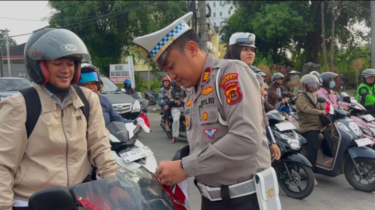 Kasat Lantas Polresta Jambi AKP Hadi Siswanto memasang bendera merah putih di kendaraan salah satu pengendara di Simpang Jelutung, Jambi, Rabu (6/8/2025).(Dok.Stepanus)