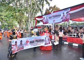 Peserta dari Kwartir Ranting Danau Sipin membawa spanduk bertema Semarak Hari Pramuka ke-64 saat melintas di depan panggung kehormatan di kawasan Tugu Keris Siginjai, Kota Jambi, Sabtu (9/8/2025). (Dok.Stepanus)