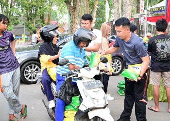 Petugas membagikan beras SPHP kepada warga dalam Gerakan Pangan Murah yang digelar Polda Jambi di kawasan Tugu Keris, Kota Jambi, Minggu (10/8/2025). (Dok.Nahar)
