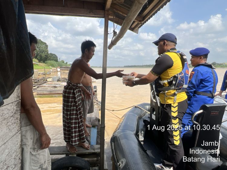 Personel Ditpolairud Polda Jambi menyerahkan bantuan makanan kepada warga pesisir Sungai Batanghari, Jumat (1/8/2025). (Dok. Humas)