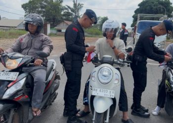 Personel Brimob Polda Jambi membagikan bendera merah putih kepada pengendara motor di Muaro Jambi, Sabtu (2/8/2025). (Dok. Nahar)