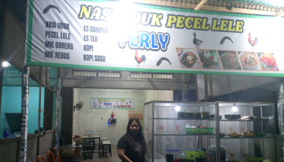 Pemilik warung, Yuli, berdiri di depan “Nasi Uduk Pecel Lele FERLY” di Desa Tangkit, Muaro Jambi. (Dok .Daus)