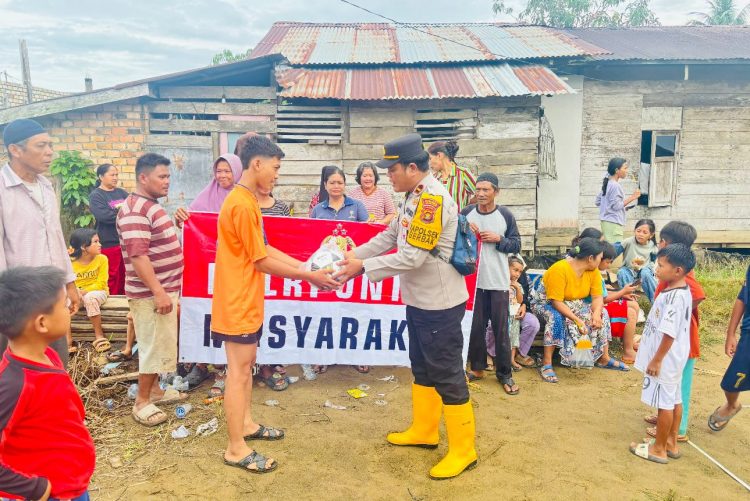 Kapolsek Berbak Ipda Hans Simangunsong menyerahkan bantuan paket sembako kepada warga terdampak banjir di Kelurahan Simpang, Kabupaten Tanjung Jabung Timur, Jumat (12/9/2025). (dok. Humas)