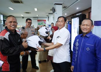 Komisaris Jasa Raharja M. Khoerur Roziqin menyerahkan helm kepada wajib pajak tertib sebagai simbol kampanye keselamatan berkendara saat kunjungan kerja di Samsat Kota Semarang III, Senin (29/9/2025). (Dok. Humas JR)