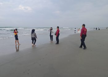 Anggota Ditpamobvit Polda Bengkulu berdialog dengan wisatawan saat melaksanakan patroli di Pantai Pasir Putih, Bengkulu, Minggu (12/10/2025). (Dok. Yola)