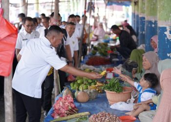 Bupati Kerinci Monadi menyerahkan hasil pertanian kepada warga saat meninjau Pasar Harian Desa Pasar Senen, Kecamatan Siulak, Rabu (15/10/2025). (Dok. Deko)