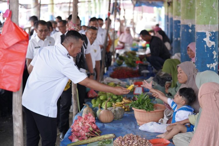 Bupati Kerinci Monadi menyerahkan hasil pertanian kepada warga saat meninjau Pasar Harian Desa Pasar Senen, Kecamatan Siulak, Rabu (15/10/2025). (Dok. Deko)