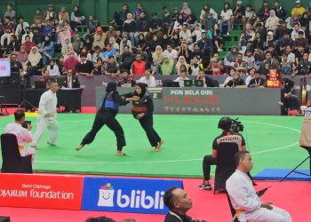 Pesilat putri Jambi, Andhini Ayu Puspita Dewi (sabuk biru), bertarung melawan Indri Bulqis dari NTB pada babak perempat final cabang pencak silat PON Bela Diri di GOR Djarum, Kudus, Minggu (19/10/2025). (Dok. Koni Jambi)