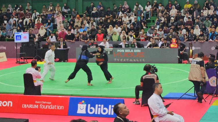 Pesilat putri Jambi, Andhini Ayu Puspita Dewi (sabuk biru), bertarung melawan Indri Bulqis dari NTB pada babak perempat final cabang pencak silat PON Bela Diri di GOR Djarum, Kudus, Minggu (19/10/2025). (Dok. Koni Jambi)