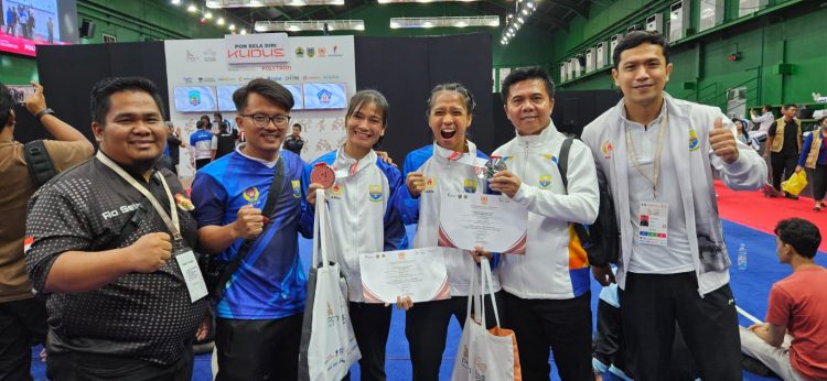 Manajer tim wushu Jambi Rio Setiadi (kiri) bersama atlet dan pelatih berpose menunjukkan medali yang diraih usai pertandingan cabang wushu pada PON Bela Diri 2025 di GOR Djarum Kaliputu, Kudus, Jawa Tengah, Minggu (26/10/2025). (Dok. Humas KONI)